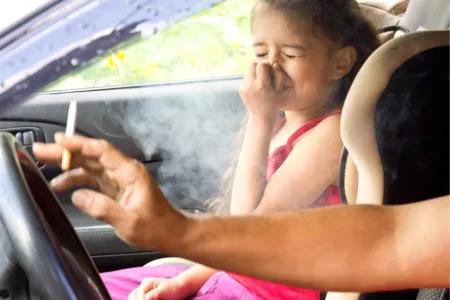 de bestuurder van een voertuig rookt aan het stuur terwijl een kind de hand voor de mond houdt 