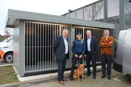 Nieuw hondenhok met daarvoor hond, hoofdinspecteur, burgemeester, gouverneur en korpschef