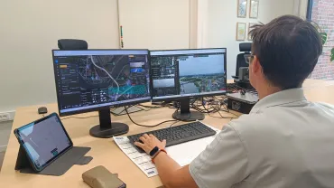 Dronepiloot die drone aanstuurt vanachter computer